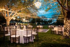 an outdoor event with tables and chairs set up for dinner under the trees at night