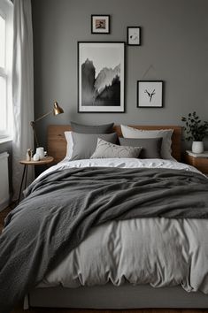 a bedroom with grey walls and pictures on the wall above the bed, along with wooden flooring