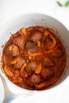 a white bowl filled with meatballs and peppers