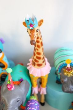 a giraffe wearing a party hat surrounded by other toy animals