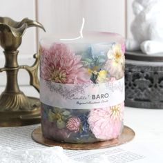 a white candle with pink and yellow flowers on it