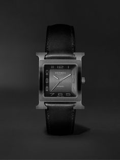 Originally created in 1996 by Philippe Mouquet, this titanium Hermès Timepieces watch already feels like a future heirloom. It has a minimalist black face that's detailed only with Arabic numerals and the house moniker at 12 o'clock. Adding to its refined appearance, it's anchored by a tonal leather strap and has Super-LumiNova®-coated hands so you can read it in even in low light. It's powered by a Calibre H1912 automatic movement, which you can see through the exhibition case back, and has a 4 Black Minimalist Watch With Rectangular Dial, Black Minimalist Watch Accessories For Formal Occasions, Minimalist Black Watch For Formal Occasions, Modern Rectangular Dial Watch Accessories For Evening, Modern Evening Watches With Rectangular Dial, Black Watches With Rectangular Dial For Evening, Modern Analog Evening Watch, Black Watch Accessories With Rectangular Dial For Evening, Modern Black Watch Accessories For Formal Occasions