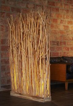 a sculpture made out of branches on top of a wooden floor next to a brick wall