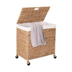 a wicker laundry hamper on wheels with a towel hanging from the top and bottom