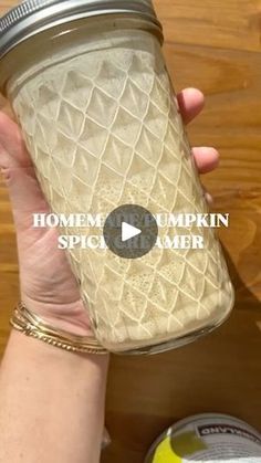 a person holding a mason jar over a wooden table