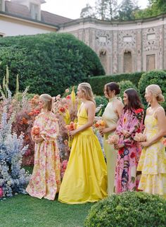 a group of women standing next to each other in front of flowers