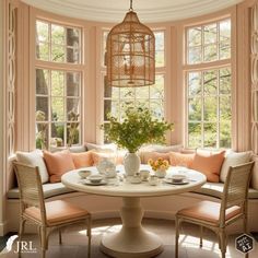 a breakfast nook in the corner of a room with round table and wicker chairs