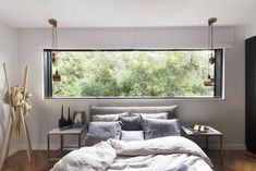 a bed sitting under a large window next to a wooden floor