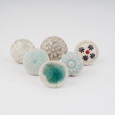 five ceramic knobs with designs on them sitting next to each other in front of a white background