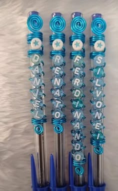 four blue and silver pens with letters on them