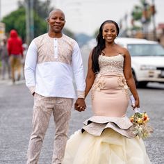 a man and woman holding hands while walking down the street