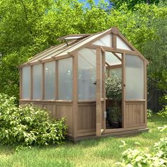 a small wooden greenhouse in the middle of some grass