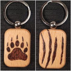 two wooden keychains with animal prints on them, one has a bear's paw