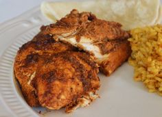 two pieces of fried chicken on a plate with rice