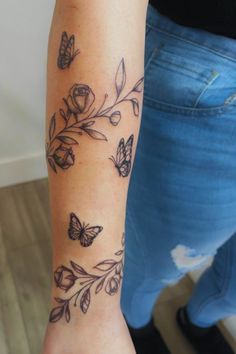 a woman's arm with butterflies and flowers tattooed on the side of her arm