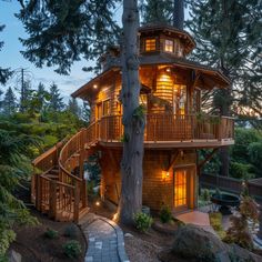 a tree house is lit up at night in the woods with stairs leading to it