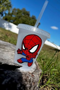 a plastic cup with a spider - man design on it sitting on a piece of wood