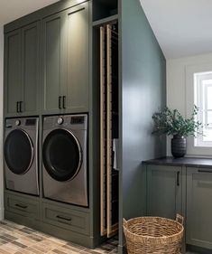 a washer and dryer in a laundry room with green cabinetry, wood flooring and white walls