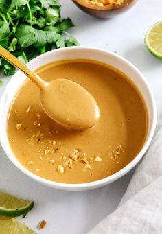 a spoon in a bowl filled with peanut sauce and garnished with cilantro