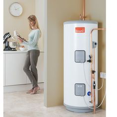 a woman is standing in front of a water heater and looking at something on the counter