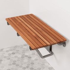 a wooden bench sitting on top of a tiled floor next to a white tile wall