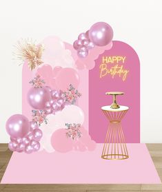 a happy birthday card with balloons and a cake on a stand in front of a pink backdrop