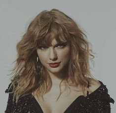 a close up of a person with long hair and red lipstick on her face, wearing a black dress