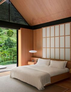 a large bed sitting in a bedroom next to a sliding glass door that leads out onto a lush green hillside