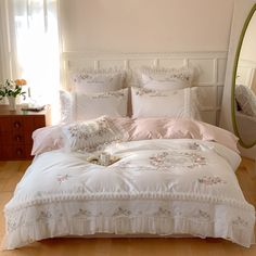 a bed with white comforter and pillows in a bedroom next to a mirror on the wall