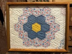 an old quilt is displayed in a wooden frame on a table next to some wood boxes