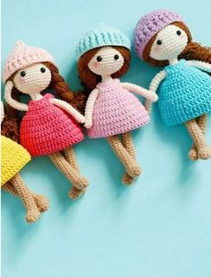 three crocheted dolls sitting next to each other on top of a blue surface