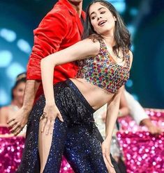 a man and woman dancing on stage with pink sequins in the back ground