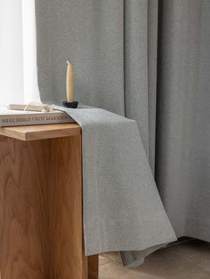 a table with a candle on it next to a curtain