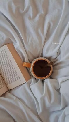 an open book and cup of coffee on a bed