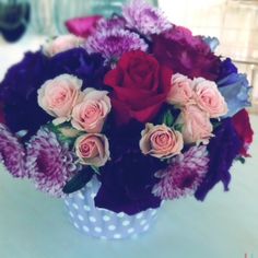 a vase filled with lots of purple and pink flowers on top of a white table