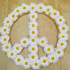 a peace sign made out of daisies on a tile floor in the shape of a circle