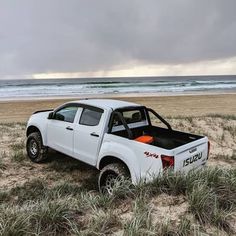 a white pick up truck parked on top of a sandy beach next to the ocean