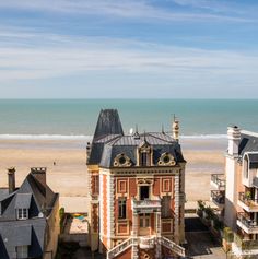 an old building on the beach next to some buildings with balconies and windows