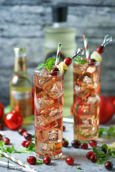 two glasses filled with drinks sitting on top of a table next to bottles and candy canes