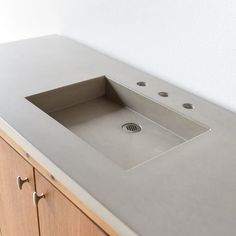 a bathroom sink sitting on top of a counter next to a wooden cabinet and white wall