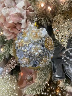 an ornament hanging from a christmas tree decorated with pearls and swaroons