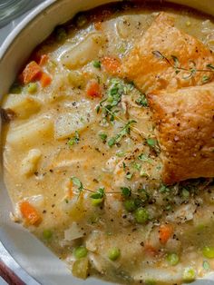 a white bowl filled with chicken pot pie soup and bread on top of the bowl