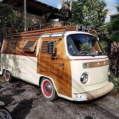 an old vw bus with wood paneling parked in front of some trees and bushes