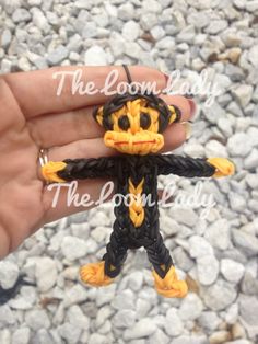 a hand is holding a small toy that looks like a monkey with yellow and black accents