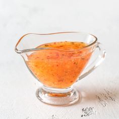 a small glass bowl filled with sauce on top of a white tableclothed surface