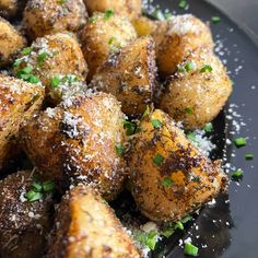 a black plate topped with fried potatoes covered in parmesan sprinkles