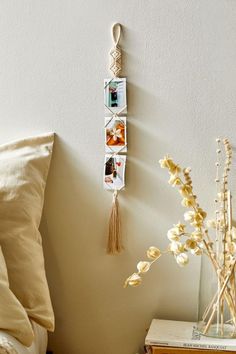 a white wall hanging with pictures and flowers on it next to a bed in a bedroom