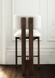 a white chair sitting in front of a wall with a wooden frame on top of it