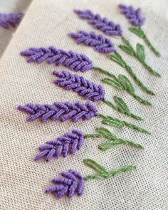 lavender flowers are stitched together on a piece of linen