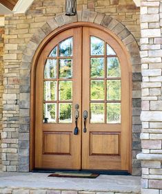 an arched wooden door in front of a stone building